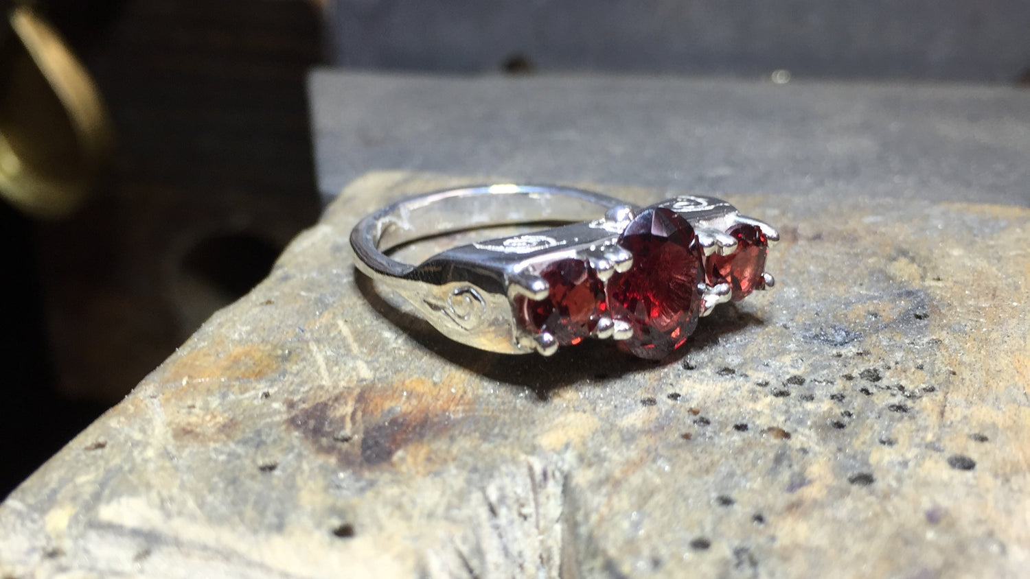 Silver ring with red gemstones on a metal surface