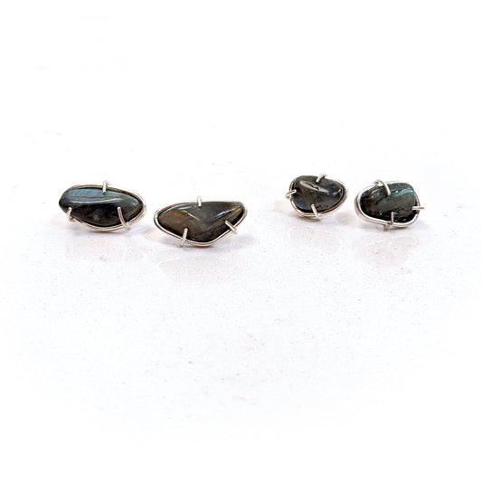 Full view of small and large Cassius Studs laying next to one another on a white background.