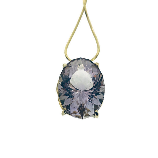 Detail shot of pendant on Amethyst Pendant. This necklace showcases an oval amethyst set with four gold prongs laying on a gold snake chain.