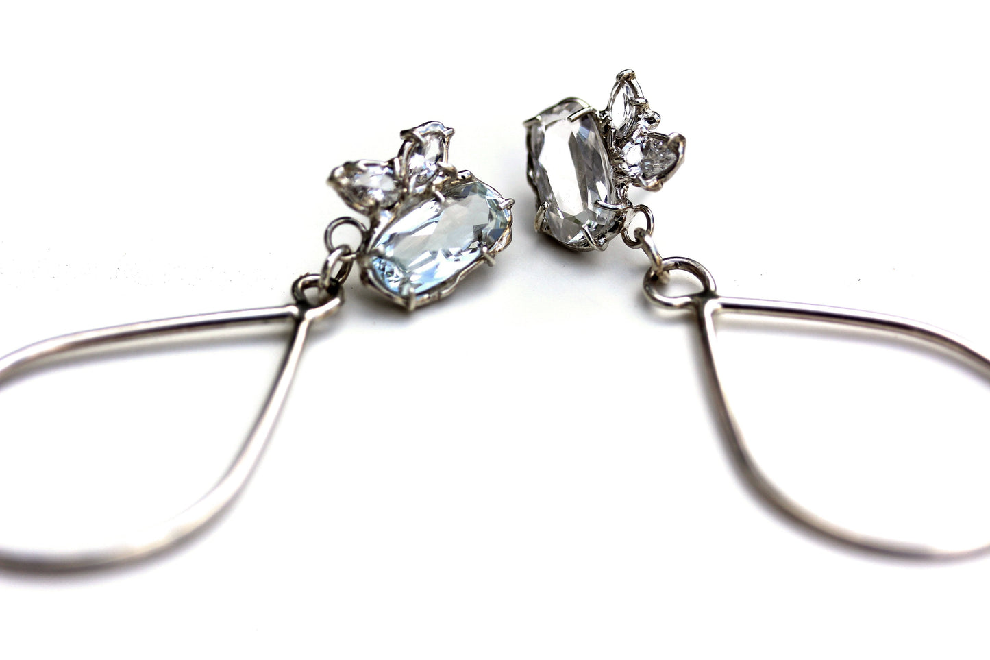 Sterling silver dangle earrings with a cluster of white topaz gemstone in various shapes and a tear drop shaped dangle.