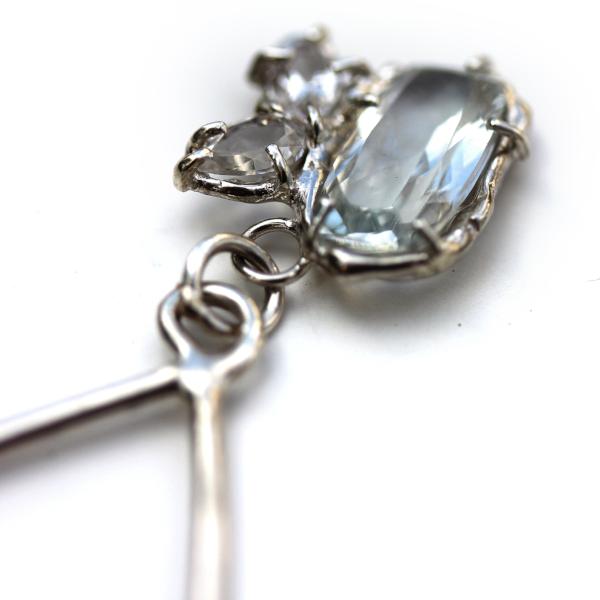 Detail photo of a silver dangle earring with a cluster of white topaz gemstones.