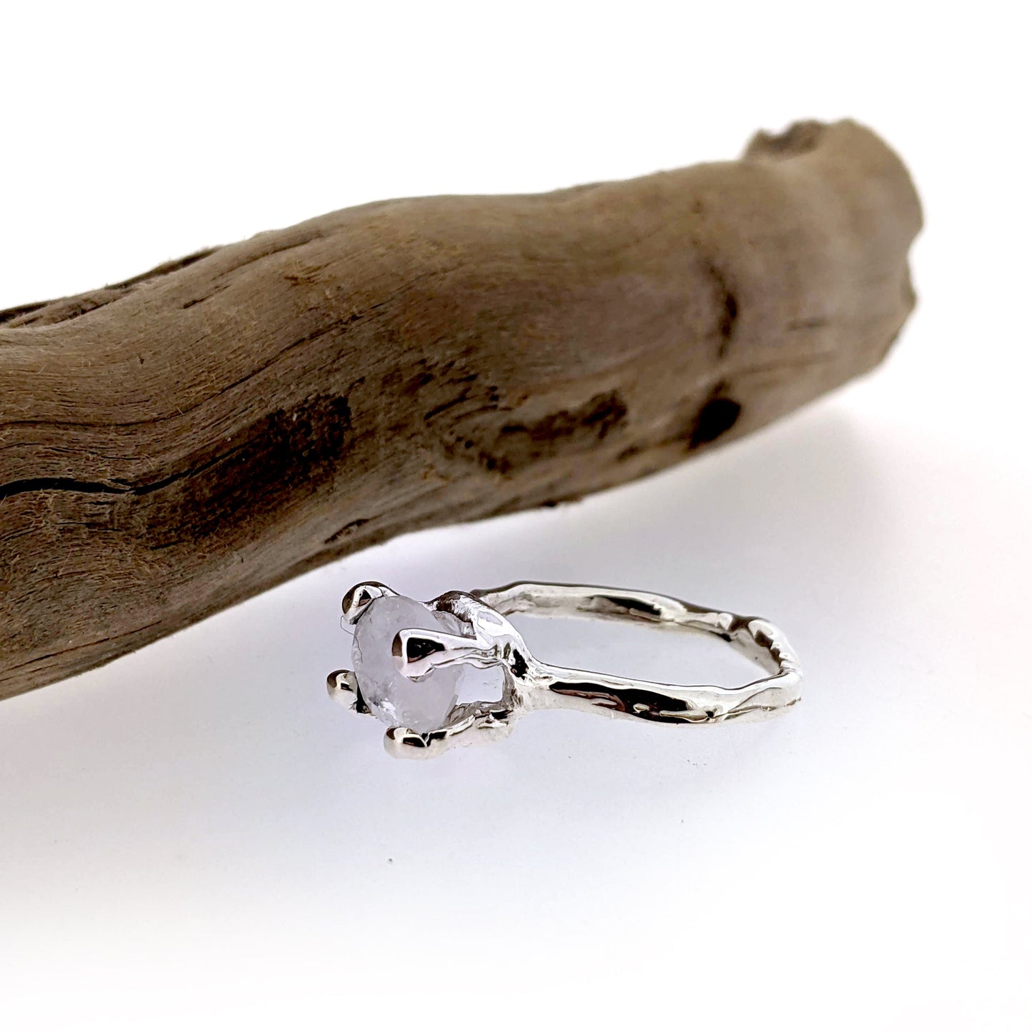 organic design rainbow moonstone and sterling silver solitaire ring, shown displayed at side angle view.