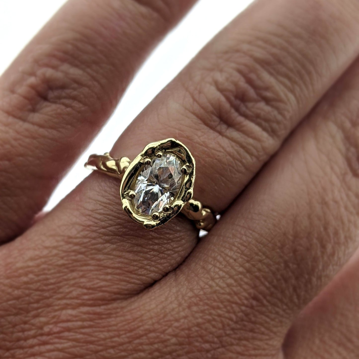 Detailed view of Annette Moissanite Ring on woman's hand to help give an idea of its scale.
