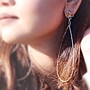 Full view of Citrine Cluster Long Earrings on woman's ear to help give an idea of their size. These earring have a set piece of citrine acting as the stud and dangling from that is a large teardrop made of silver wire.