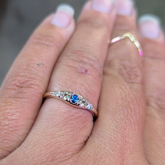 Close-up of a hand wearing a ring with a blue gemstone on a blurred background