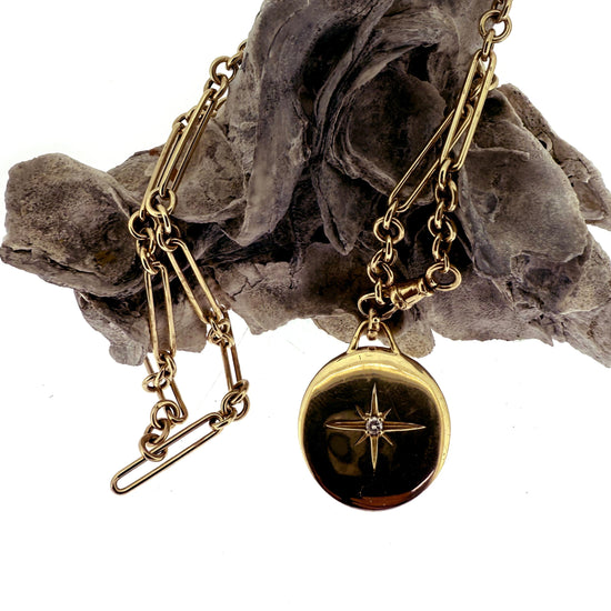 Gold necklace with a pendant on a gray floral background