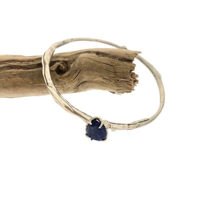 Full view of lapis shea bangle hanging off a branch.