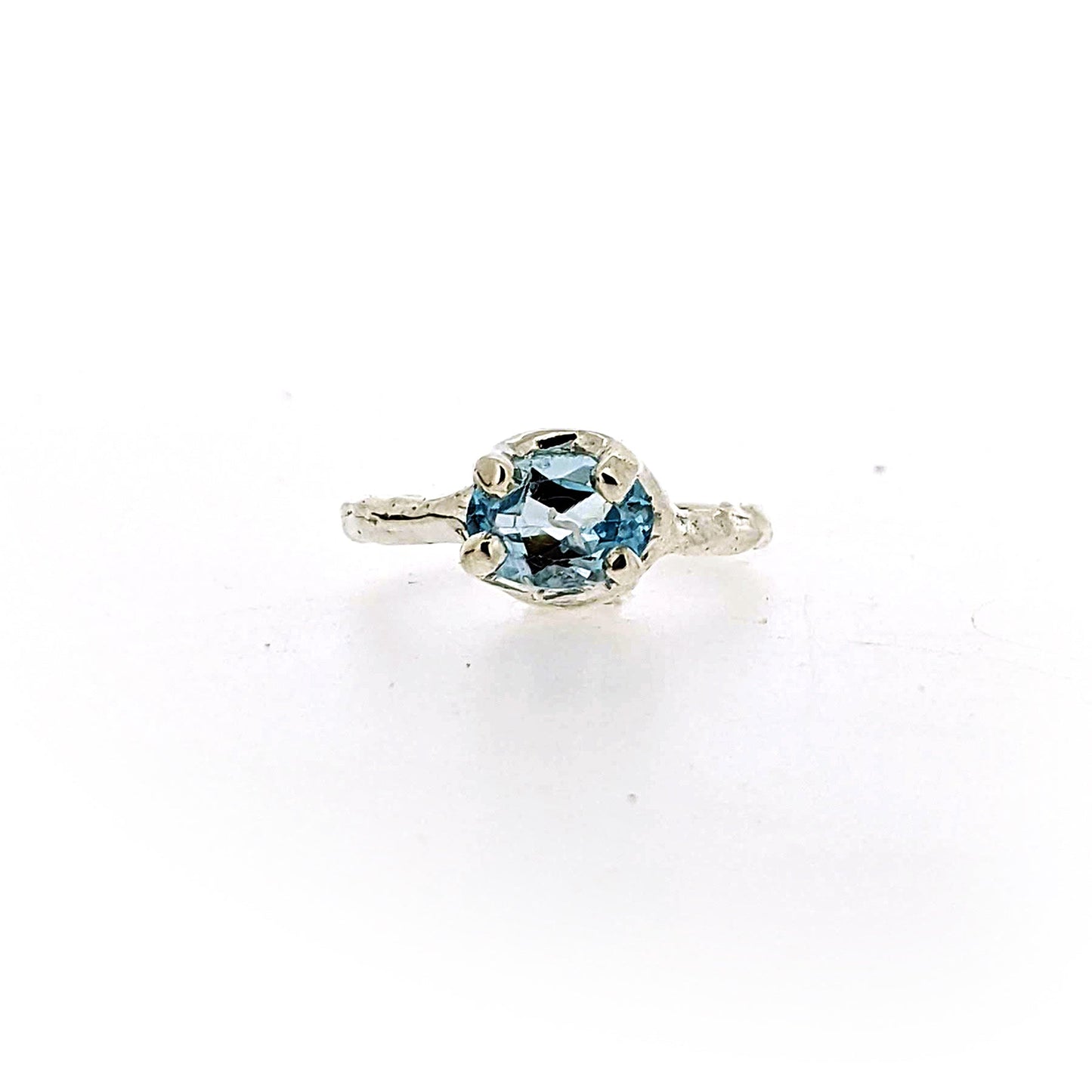 Full view of Ada Ring - Blue Topaz on white background. This ring features an ovular shaped blue topaz set with four silver prongs and lays on a silver band.