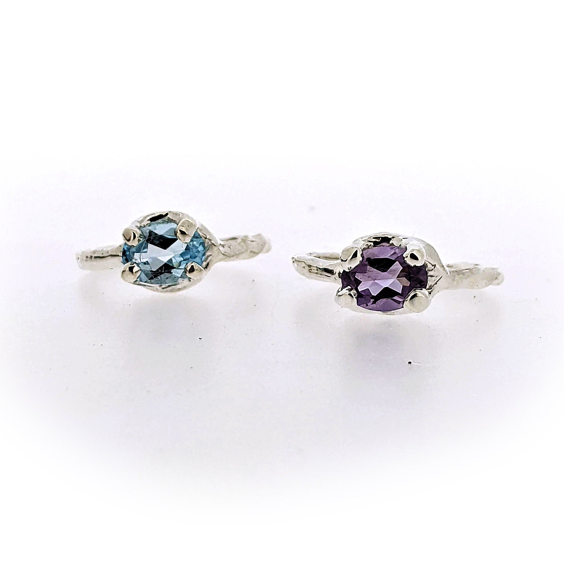 Frontal view of Blue Topaz and Amethyst Ada Rings sitting next to one another.