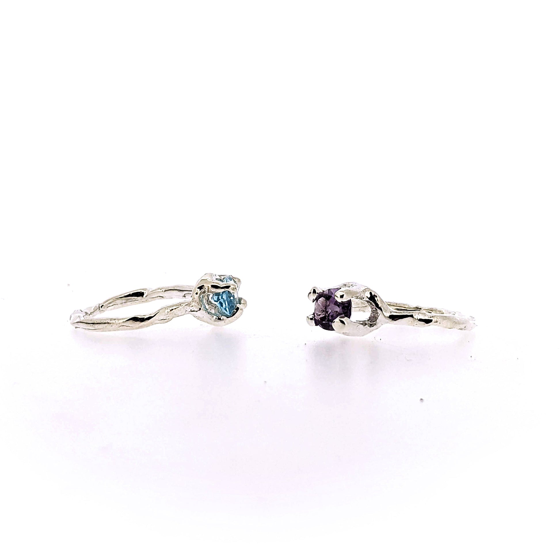 Side views of blue topaz and amethyst Ada Rings sitting next to one another.