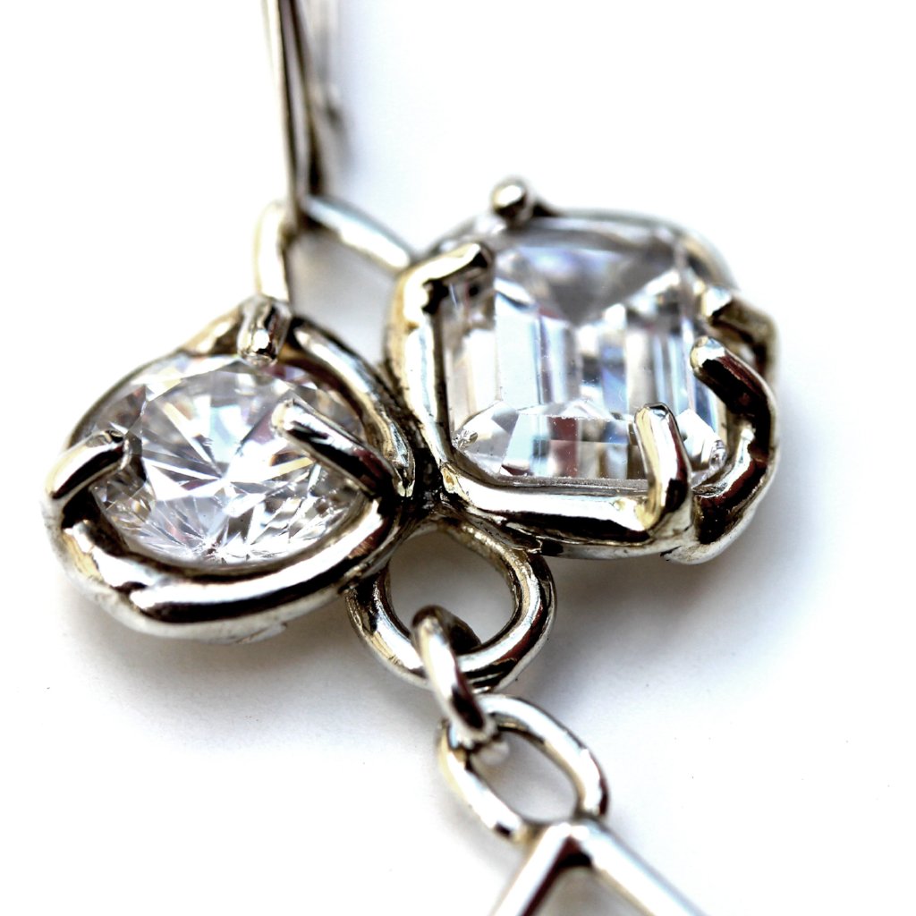 Detail of sterling silver earrings with organic prong set white topaz gemstones.