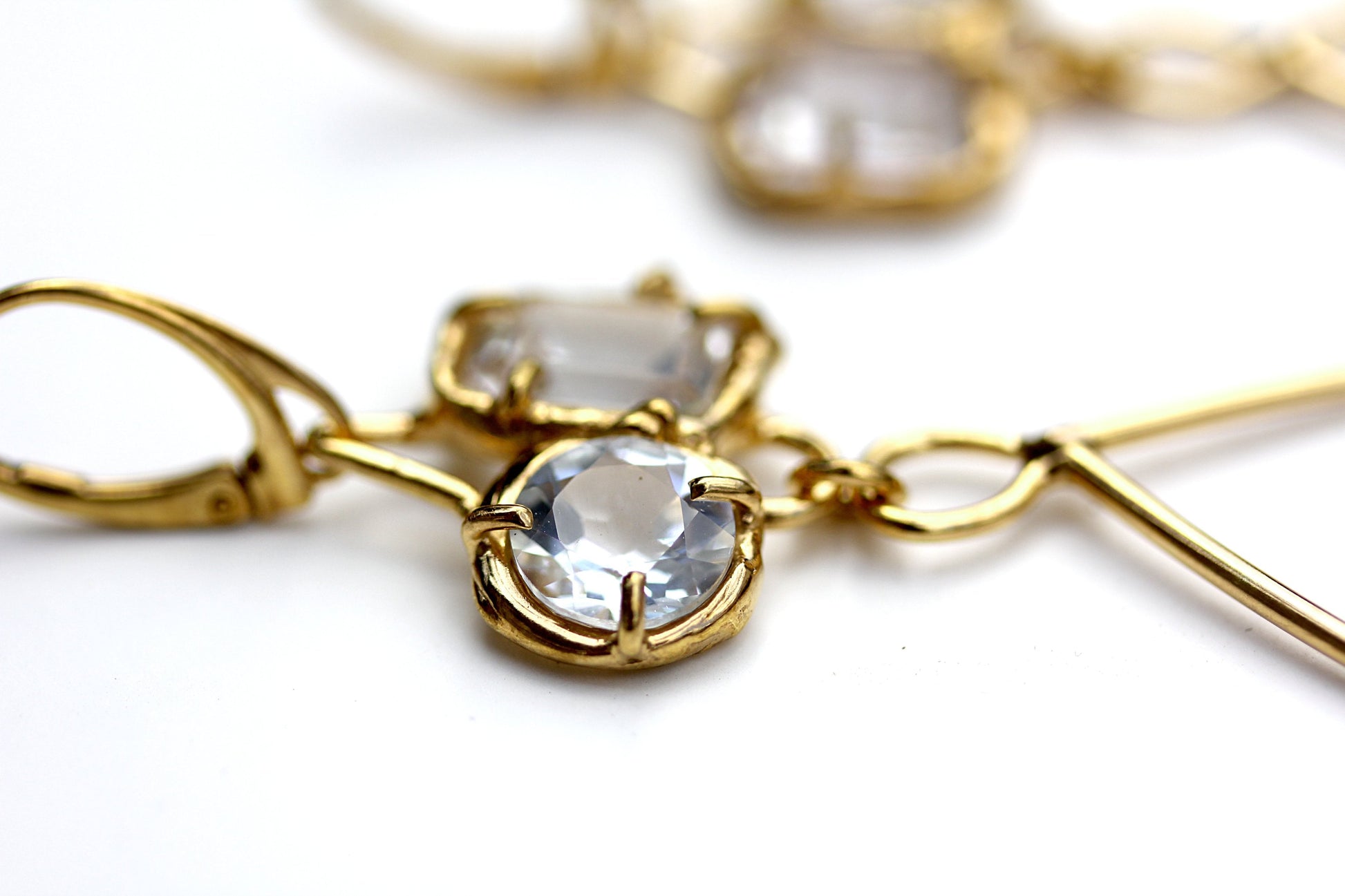 Detail photo of prong set white topaz gemstones in an organic looking earring.