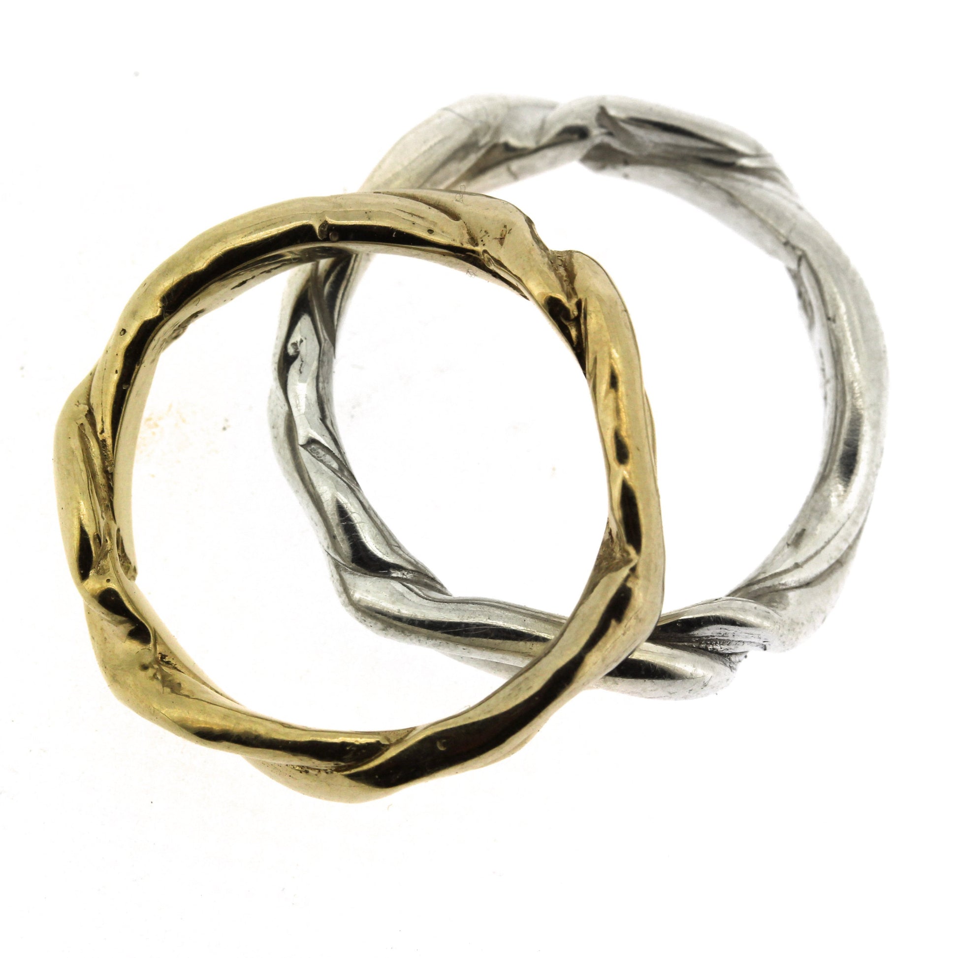 Full view of gold and silver Men's Current Bands stacked on top of one another.
