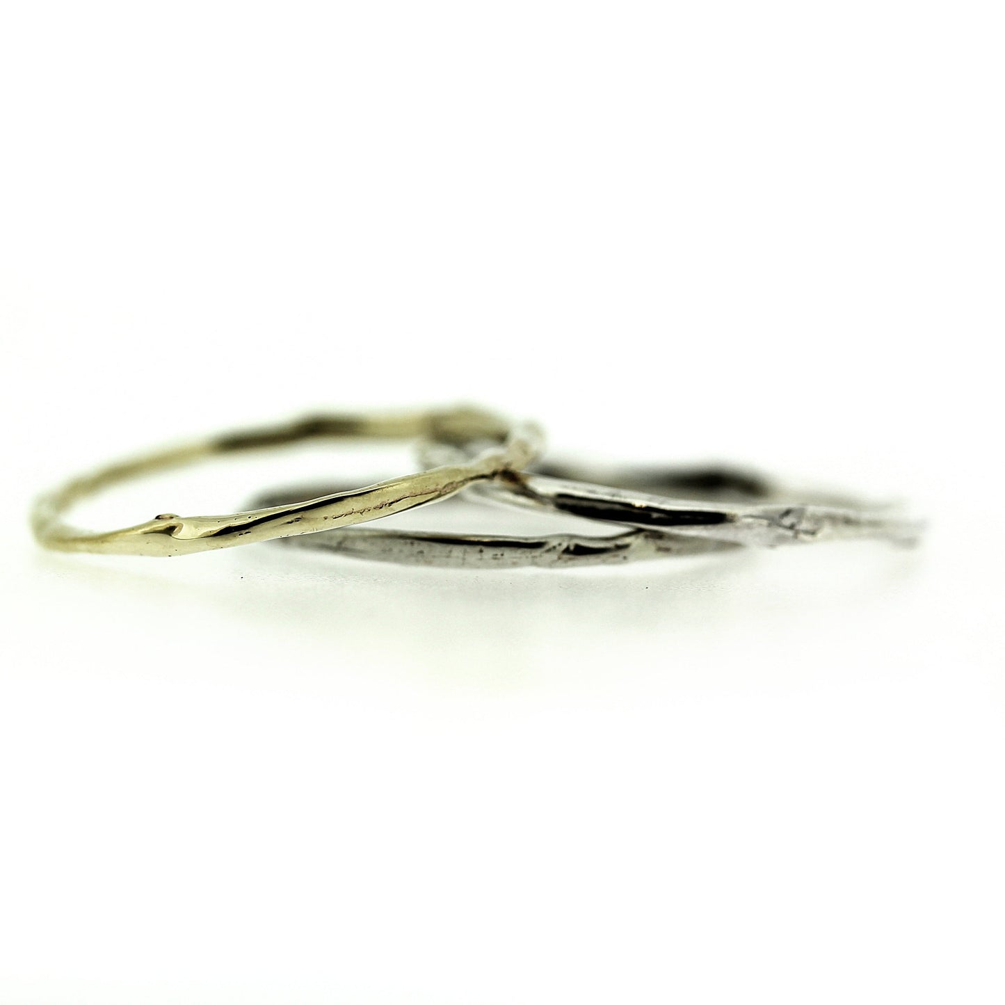 A set of three stackable rings all with the same organic texture, thin band and different colored metal.