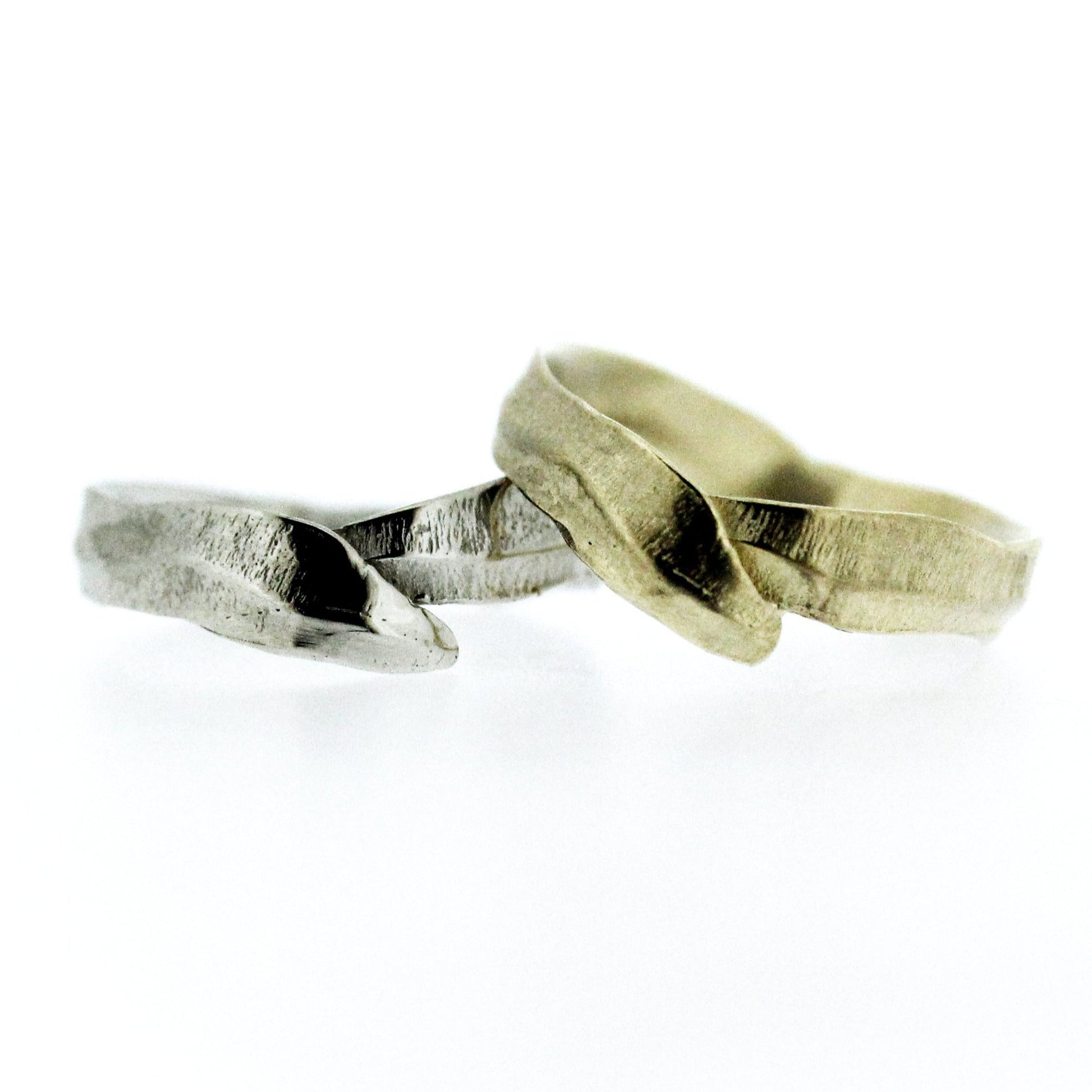 Full view of white and yellow gold Frond Arch Bands stacked on top of one another. These bands resemble the shape of leaves that curl around your finger.