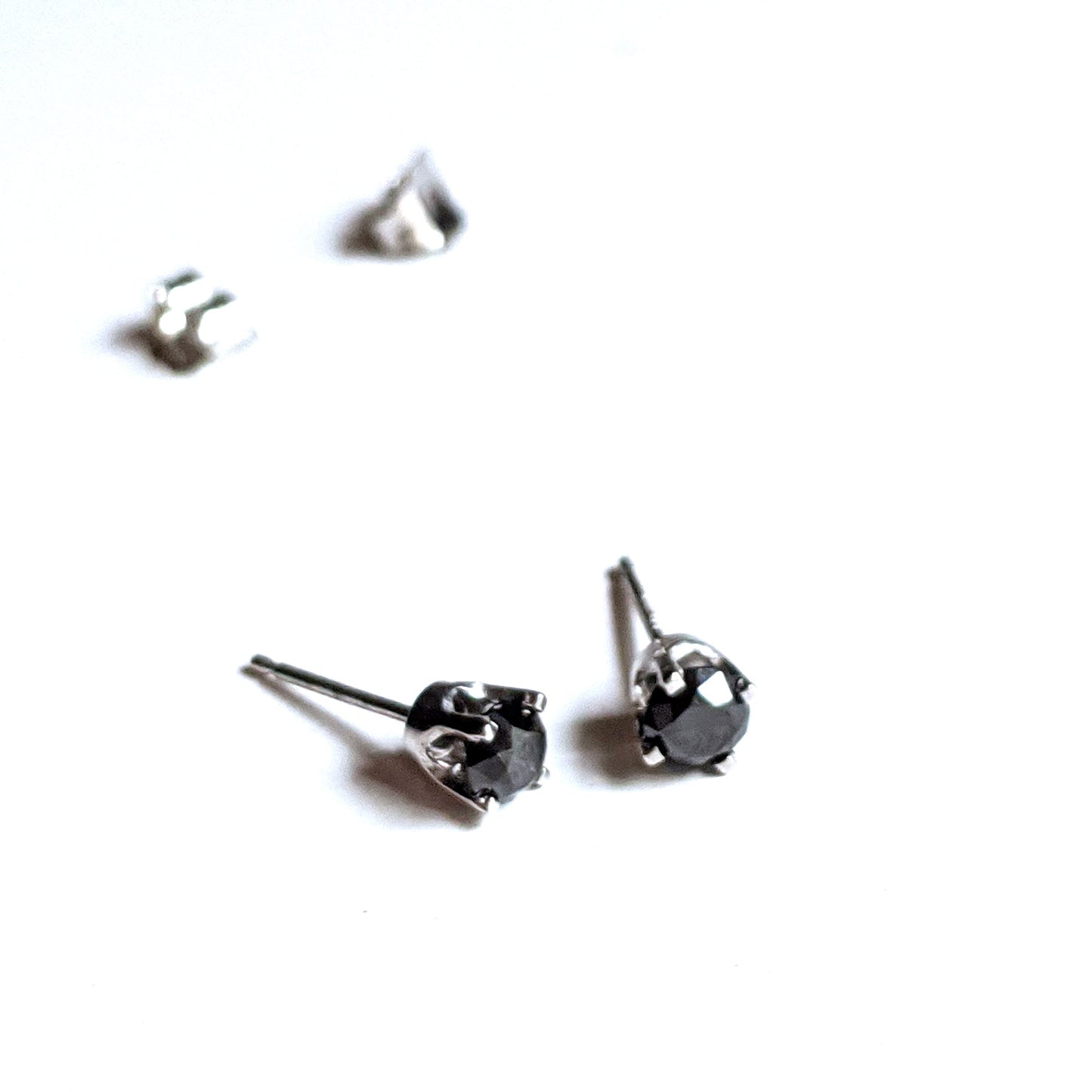Full view of top and side of Black Diamond Stud Earrings. There studs are made of white gold and have set black diamonds.