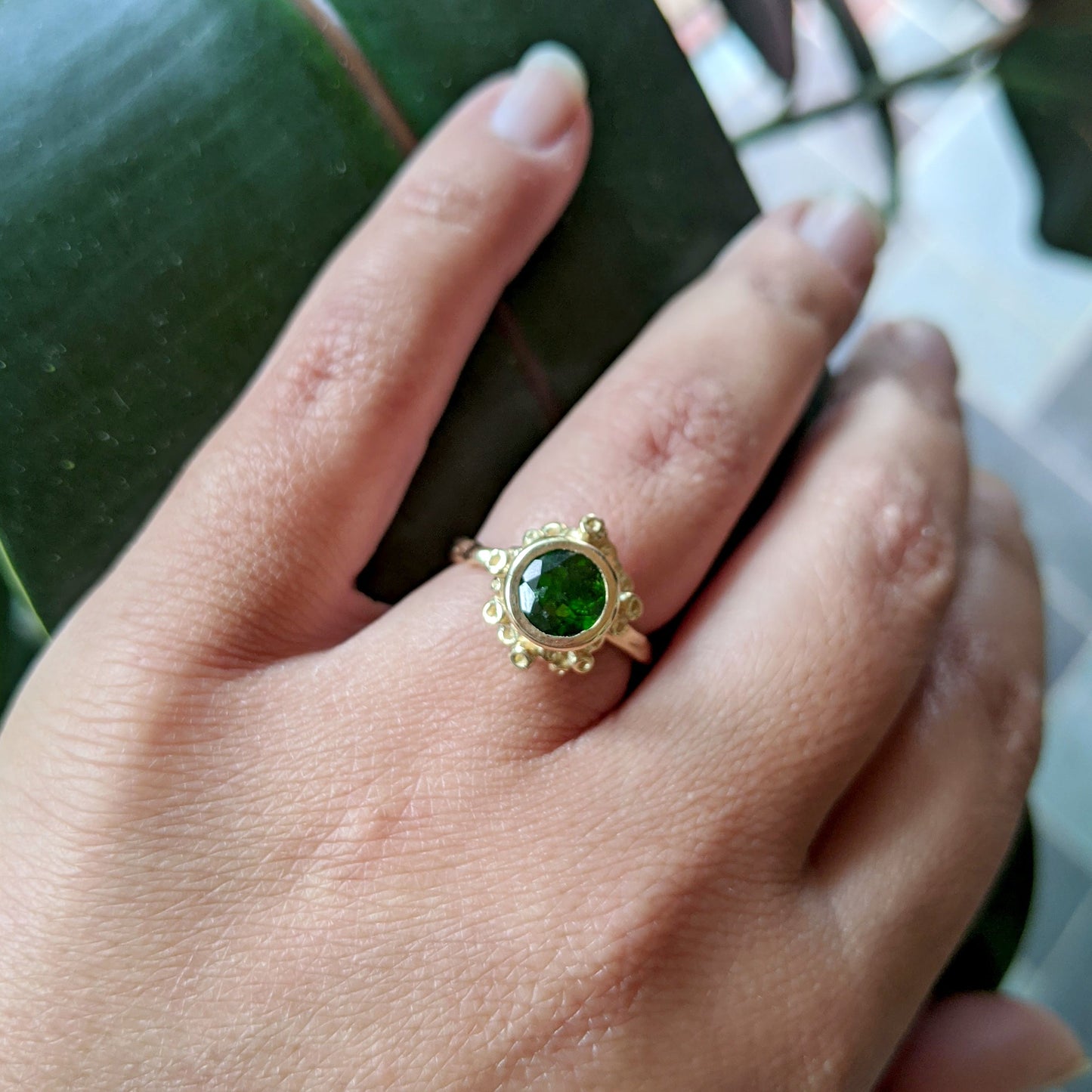Full view of Etta Ring on woman's hand to help give and idea of its scale. Hand-carved + One of a Kind. Details reminiscent of coral or sea sponge are carefully and individually sculpted to cluster around a beautiful Chrome Diopside. This unique stone is a vibrant grass green.