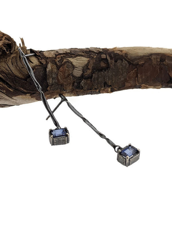 Full view of Blue Sapphire Gina Dangle Earrings hanging from a stick.