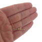 Close up view of pendant on Blank Bar Necklace with hand in background to help give idea of scale of piece. This pendant is made in yellow gold and lays on a silver chain. The pendant is in the shape of a horizontal line that resembles a branch that has two dots of gold on top of the branch.