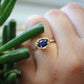 Full view of Gianna Ring on woman's hand to help give an idea of its scale. This ring is made of yellow gold, has an organic texture and a set blue sapphire at its tip.