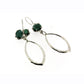 Full view of Taren Earring. These earring are asymmetrical with one showing two set opaque emerald at the top and the other only one. They both have a marquise shaped dangle bit hanging from them in silver.