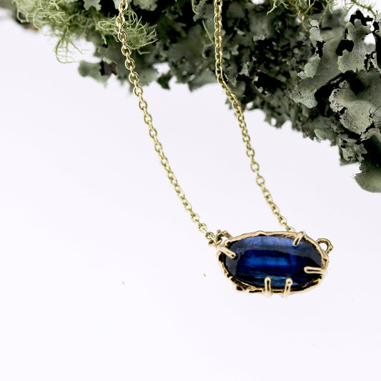 Close up view of pendant on Lark Necklace. This necklace has a set Blue Kyanite in organic gold and lays on a gold chain.