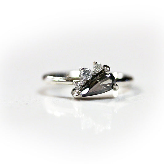 Full view of Penny Ring. One of a kind partial halo ring featuring a .59 Carat Intense Fancy Gray Moissanite set in 14K white gold.      Three dainty Lab Grown diamonds are nestled intimately next to a beautiful, unique cut pear shaped center Moissanite.  