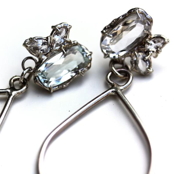 Detail photo of a silver dangle earring with a cluster of white topaz gemstones.