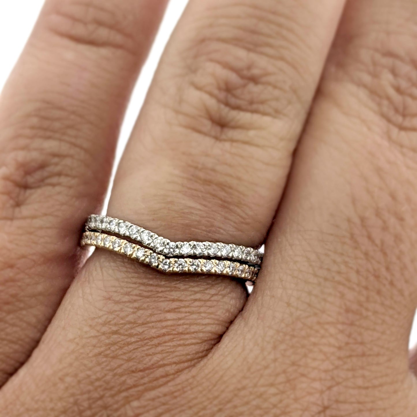 Close up view of two Karinna Arched MicroPave band rings stacked on top of one another on a woman's hand to help give an idea of its scale.