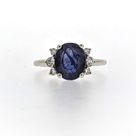 Full view of Lana Ring. A partial halo of Diamonds surrounds this large 3.95 CT Blue Sapphire that displays a stunning striated coloration pattern.  Two tiny blue sapphires appear as 'surprises' on the sides of this ring, and a subtle dappled texture sets off the entire head of the ring.  