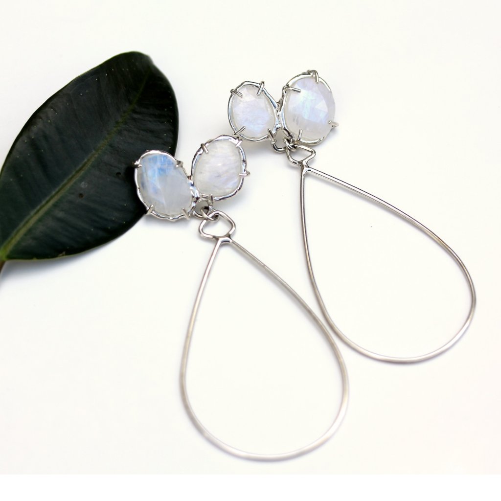 Full view of Leslee Earring - Silver. these earrings have two set rainbow moonstones at the top and dangling off of them is a teardrop shaped piece of silver wire.