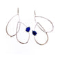 Full view of Harlow Earring - Lapis. An statement earring featuring curved tear-drop shaped forms with an organic texture resembling a smooth twig or vine with a set pear shaped lapis on each earring.