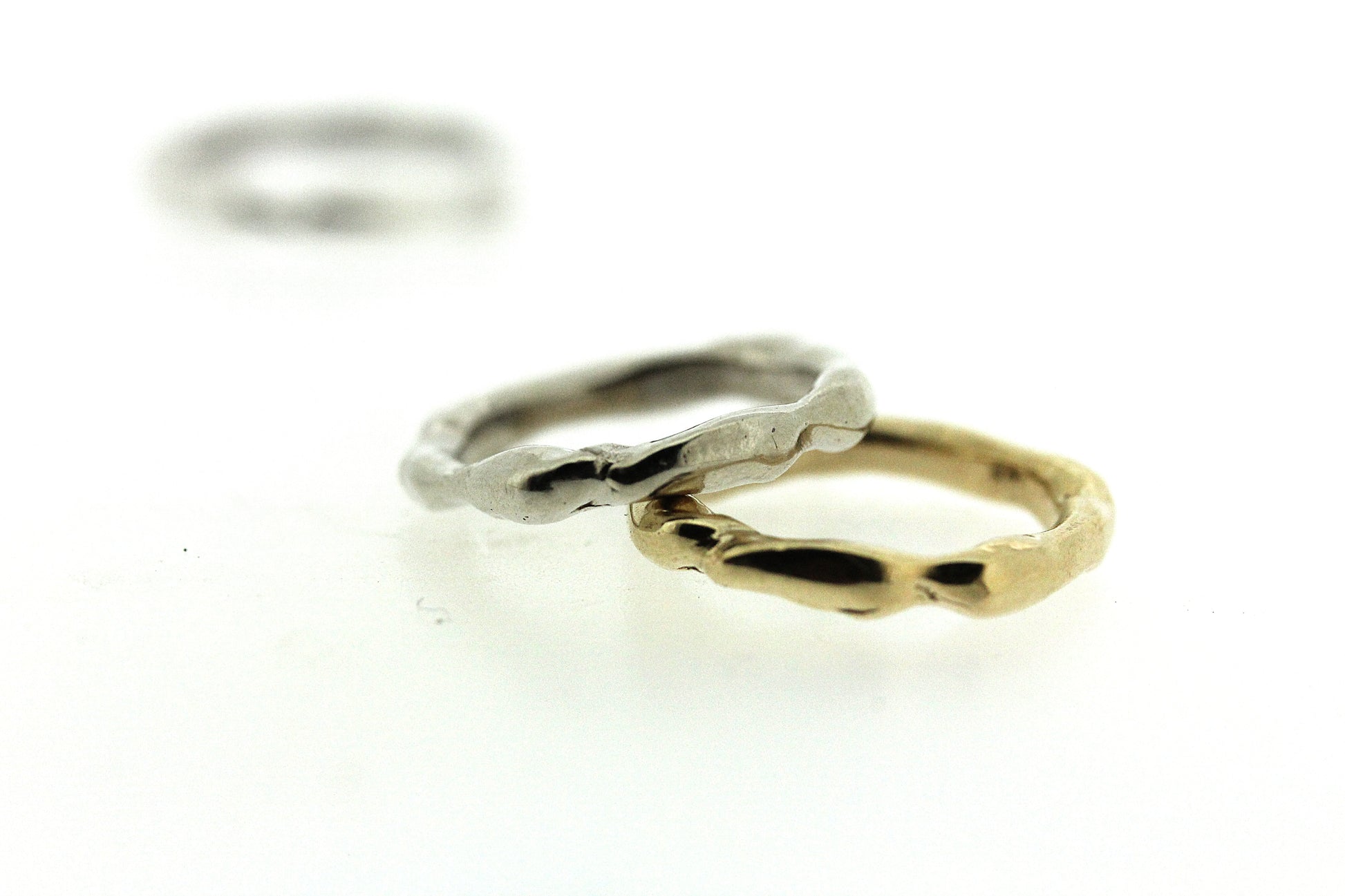 Full view of silver and gold Surge band stacked on top of one another.