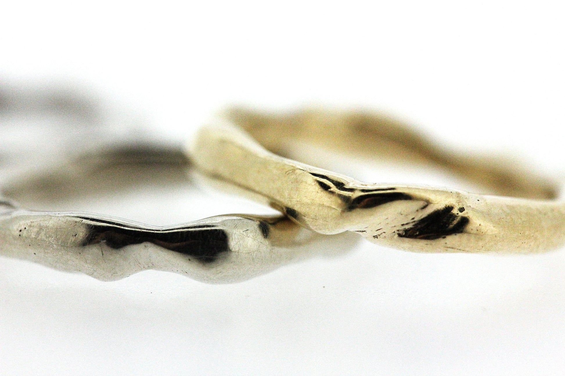 Close up view of silver and gold Surge Bands stacked on top of one another.