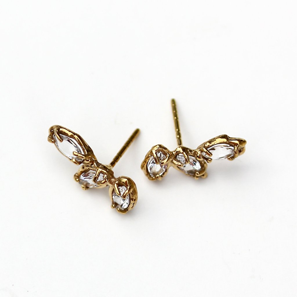 Stud earrings made of three marquise shaped white topaz stones set with organic prongs in gold.