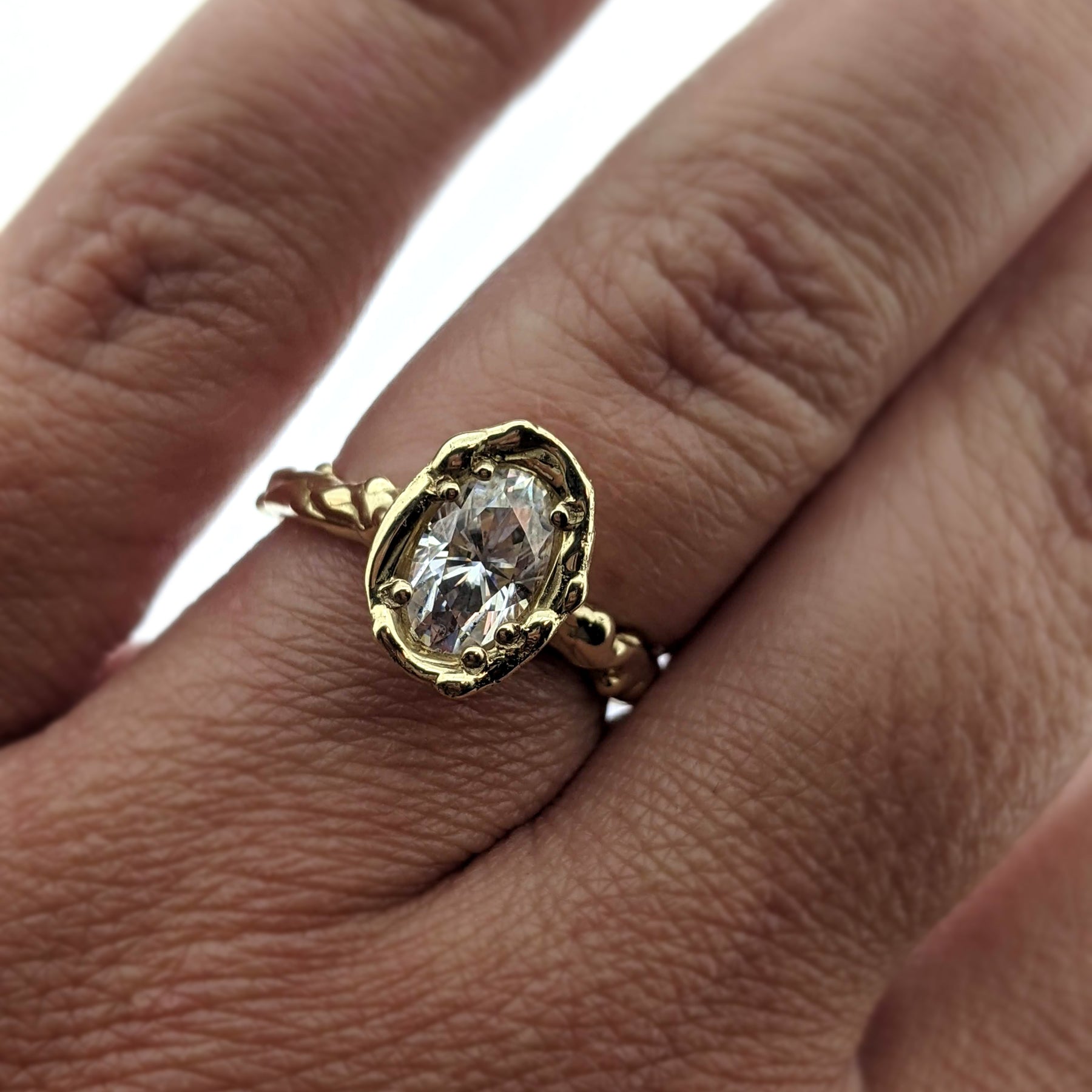 Detailed view of Annette Moissanite Ring on woman's hand to help give an idea of its scale.