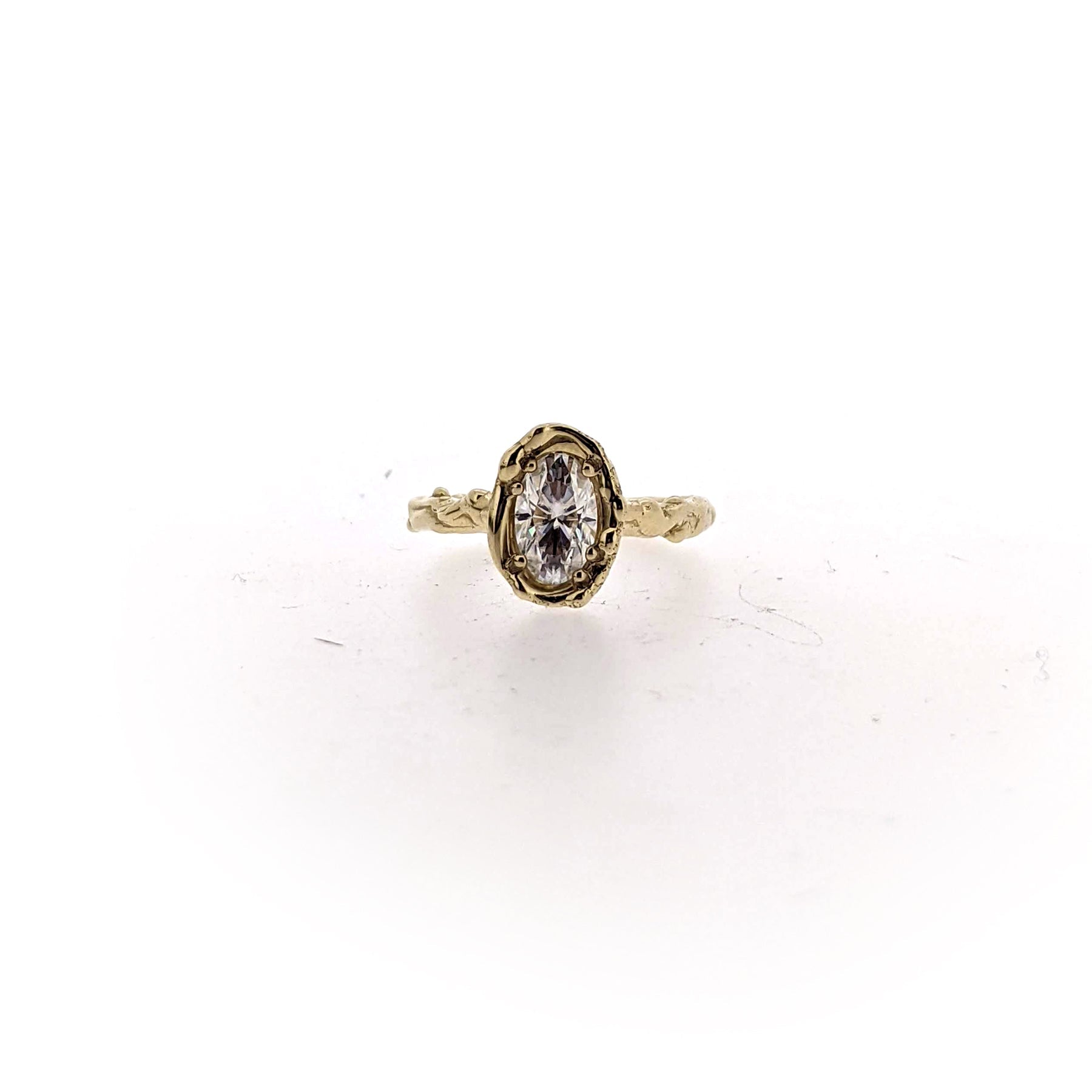 Full view of A long oval Moissanite, approximately 1.13 Carats, is set in an organic 14K Yellow Gold metal Halo.  