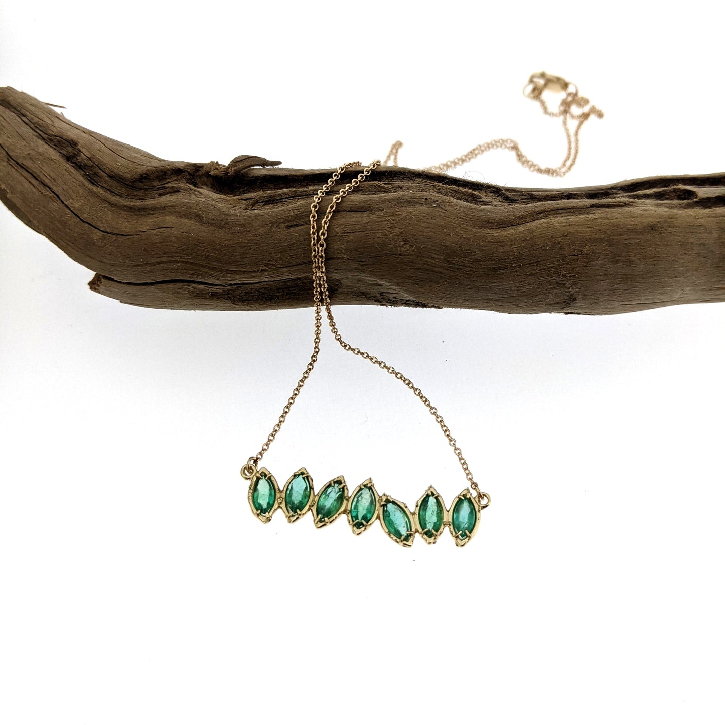 Full view of Emerald Cherin Necklace hanging from branch.