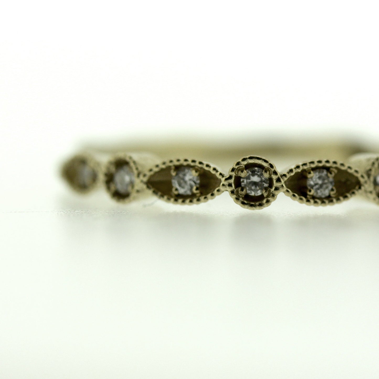 Close up view of Chloe Band. This ring is made of gold, has a hand carved design and set diamonds throughout the band.