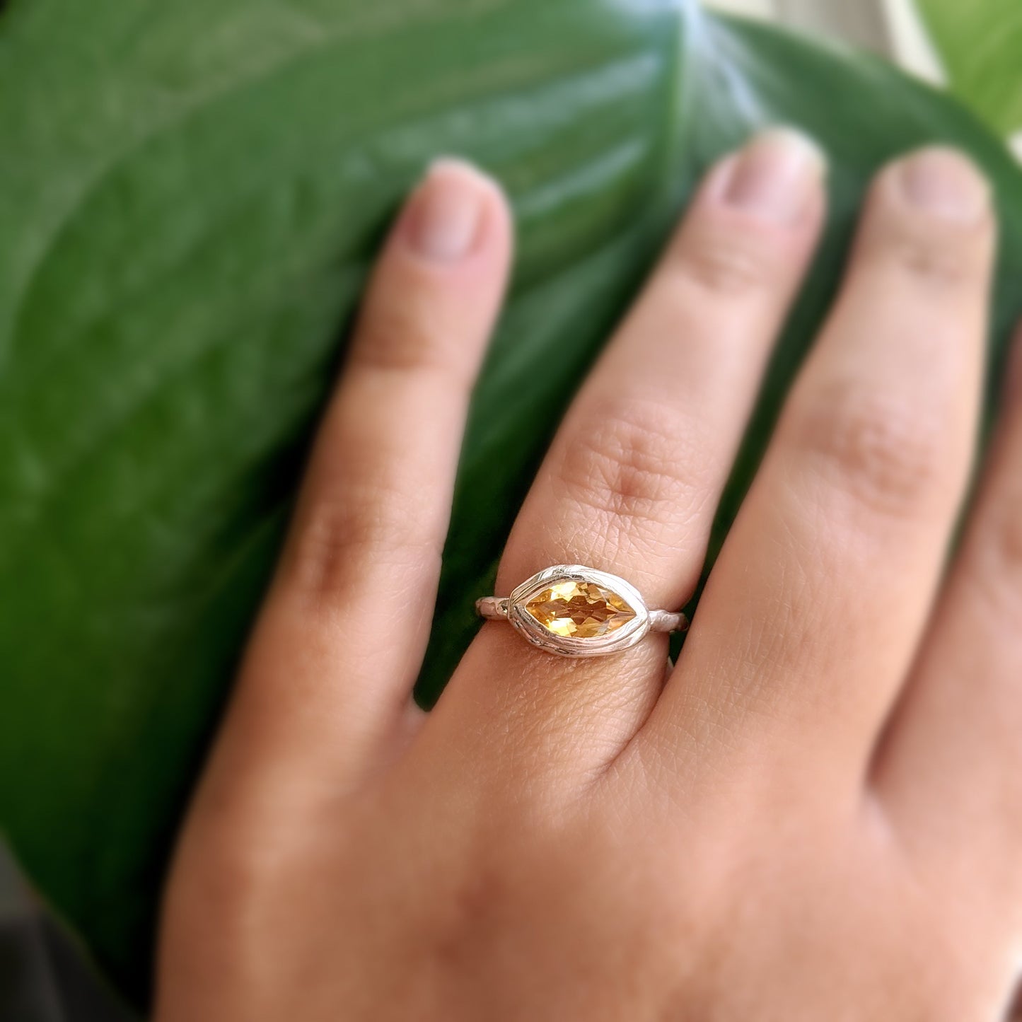 Full view of Corinna Ring on woman's hand to help give an idea of its scale. This ring is made of silver and has a set marquise shaped precious topaz at the top.