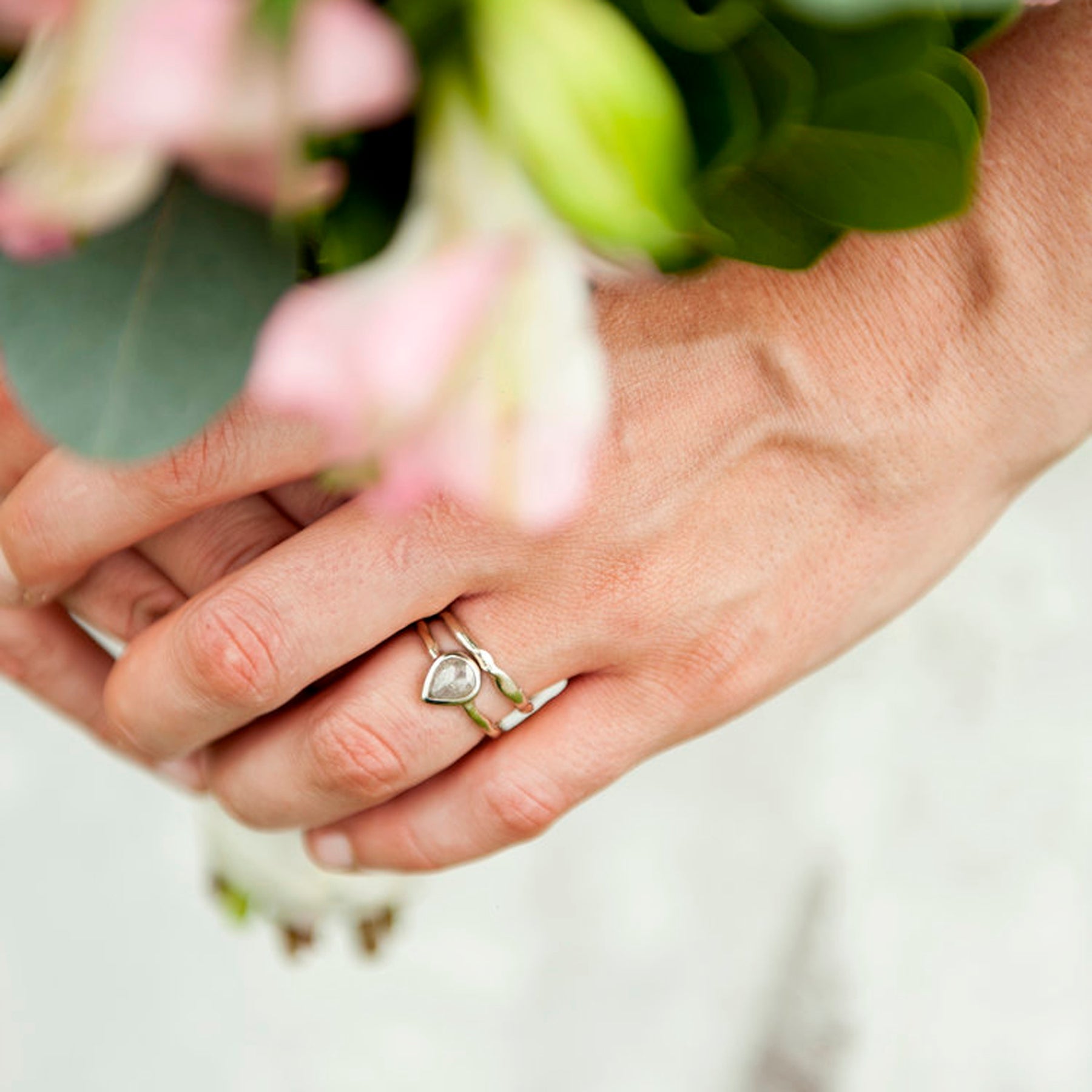 Full view of Flow Band and matching engagement ring on woman's fingers to help give an idea of their scale.