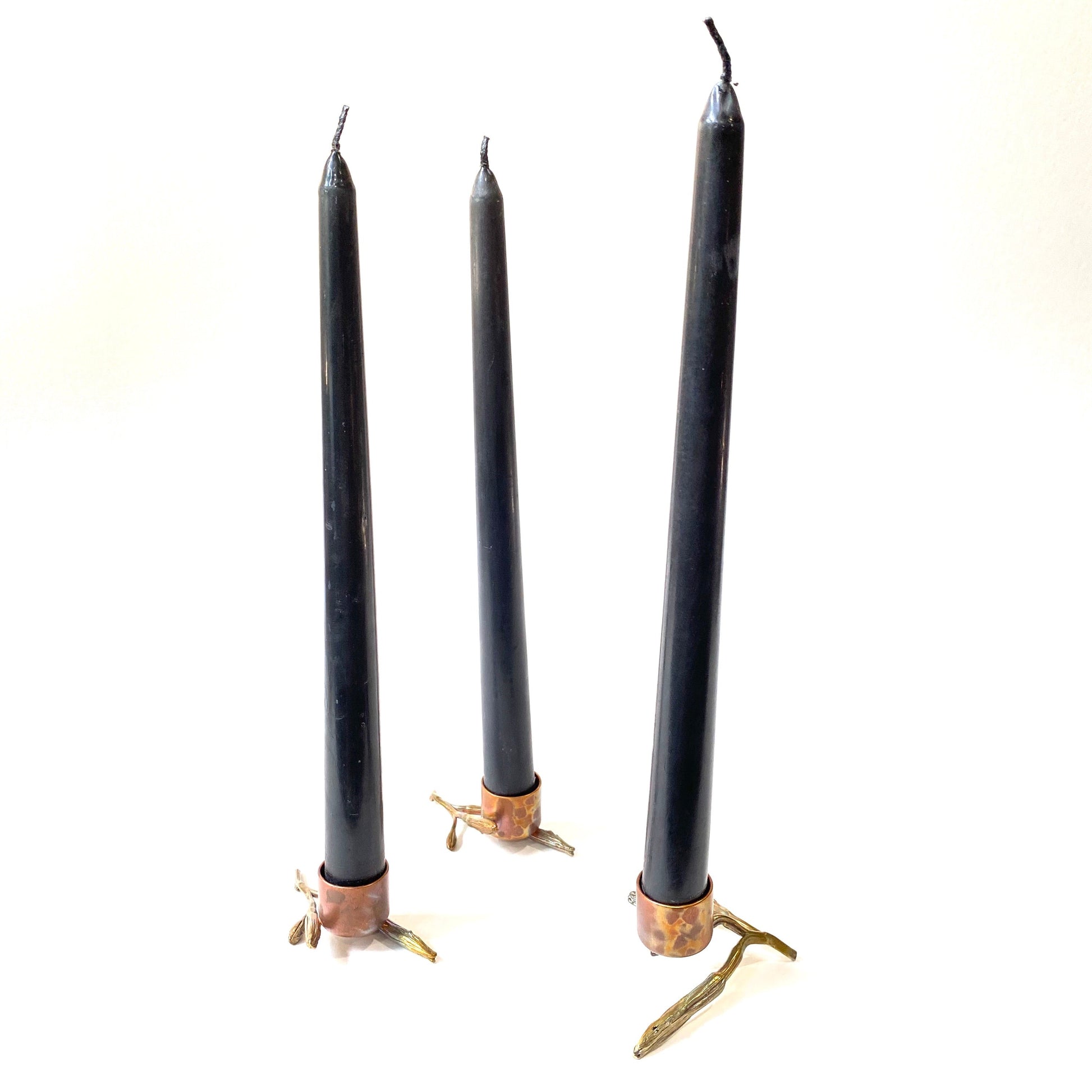 Full view of three Botanical Candlesticks with candles in them. The candlesticks are made from copper and brass and cast from water lily's.