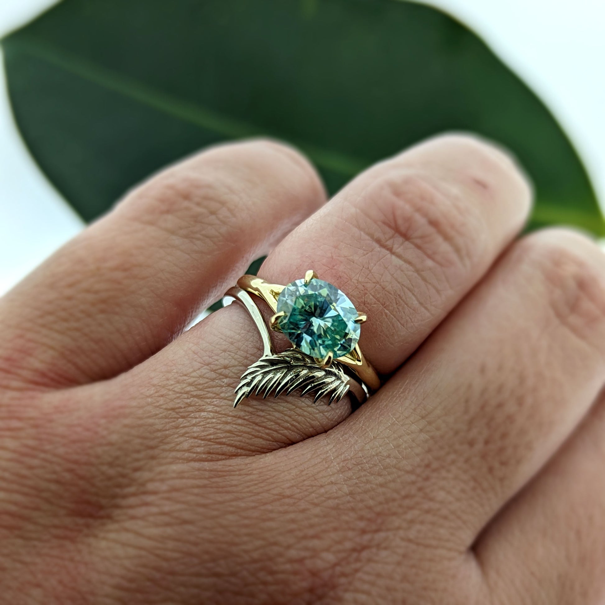 botanical leaf design nature inspired arched V shadow band wedding band, shown with teal oval horizontal east to west set teal moissanite engagement ring