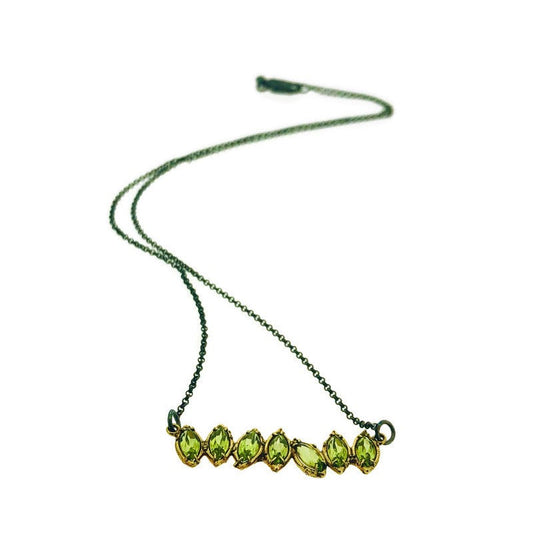 Full view of Peridot Two Tone Cherin Necklace. This necklace features seven marquise shaped peridot gems all connected to one another set in yellow gold and lays on an oxidized sterling chain.