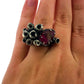 Full view of Ruby Seasponge Statement Ring on womans finger to help give an idea of its scale. This ring features a teardrop shaped lab grown ruby set in oxidized sterling. Surrounding the offset ruby are hand carved cylinders that have their centers carved out to create a texture/look of seasponge surrounding the ruby.
