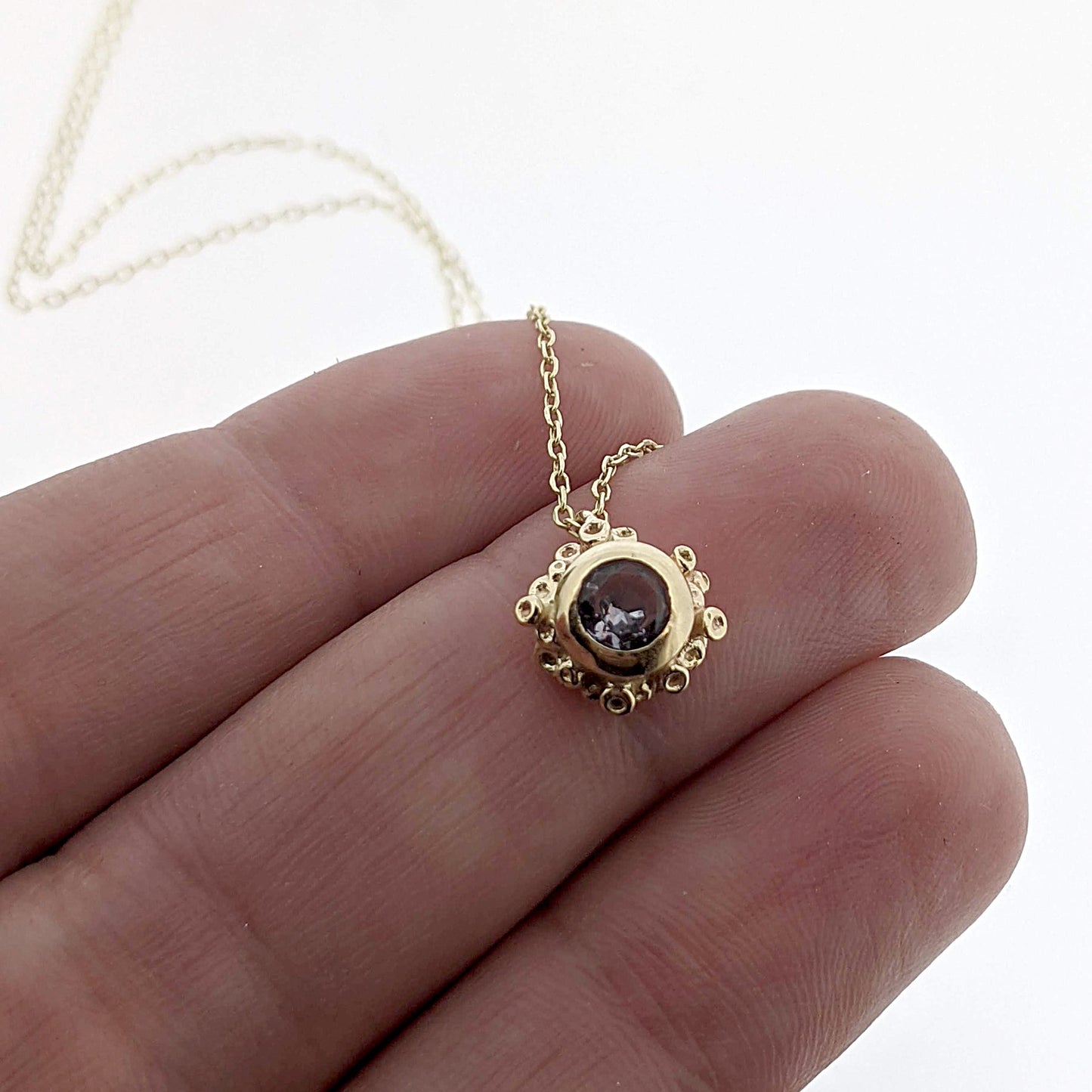 Close up view of Gray Spinel Scarlett Necklace on woman's hand to help give an idea of its scale.