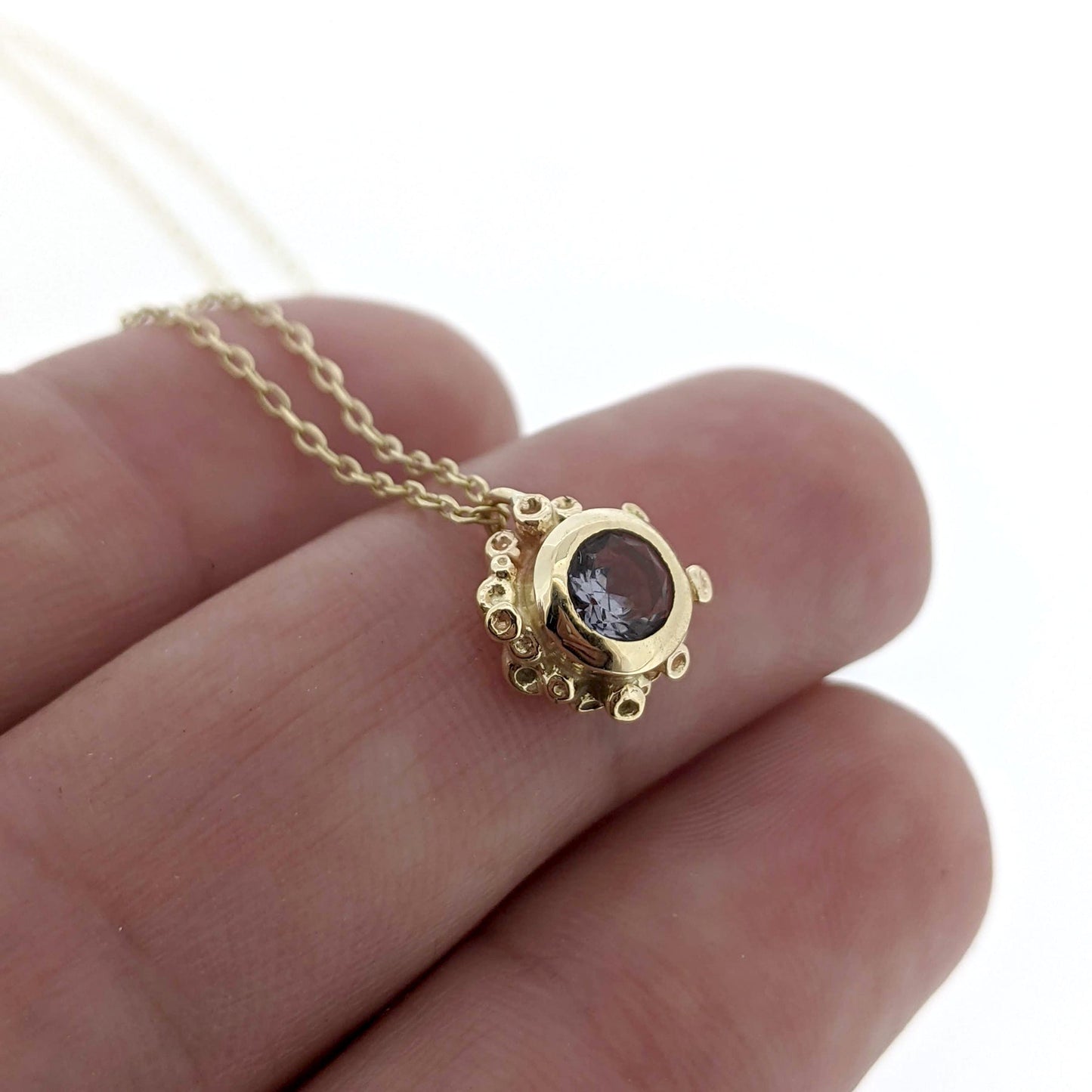 Close up view of Gray Spinel Scarlett Necklace on woman's hand to help give an idea of its scale.