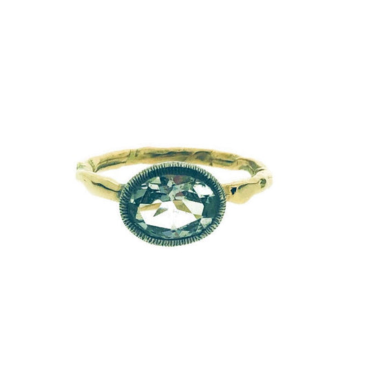 Full view of Samphire ring. This ring showcases an ovaular shaped white topaz set in sterling silver with a bezel texture and lays on an organic carved yellow gold ring.
